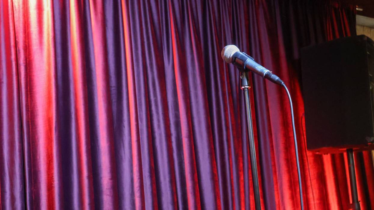 Empty Stage with Microphone and Red Velvet Curtains