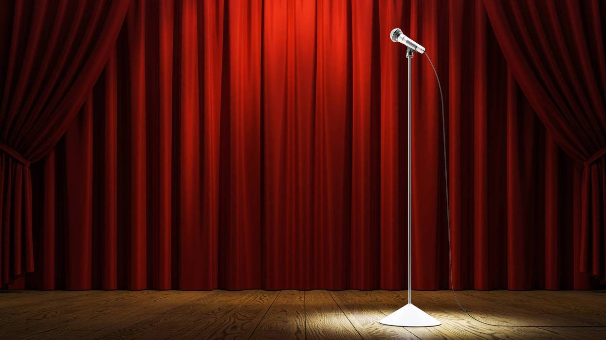 Empty stage with red curtains, spotlight on a microphone stand, with wooden floor, front view, concept of stand-up comedy or concert event. 3D Rendering