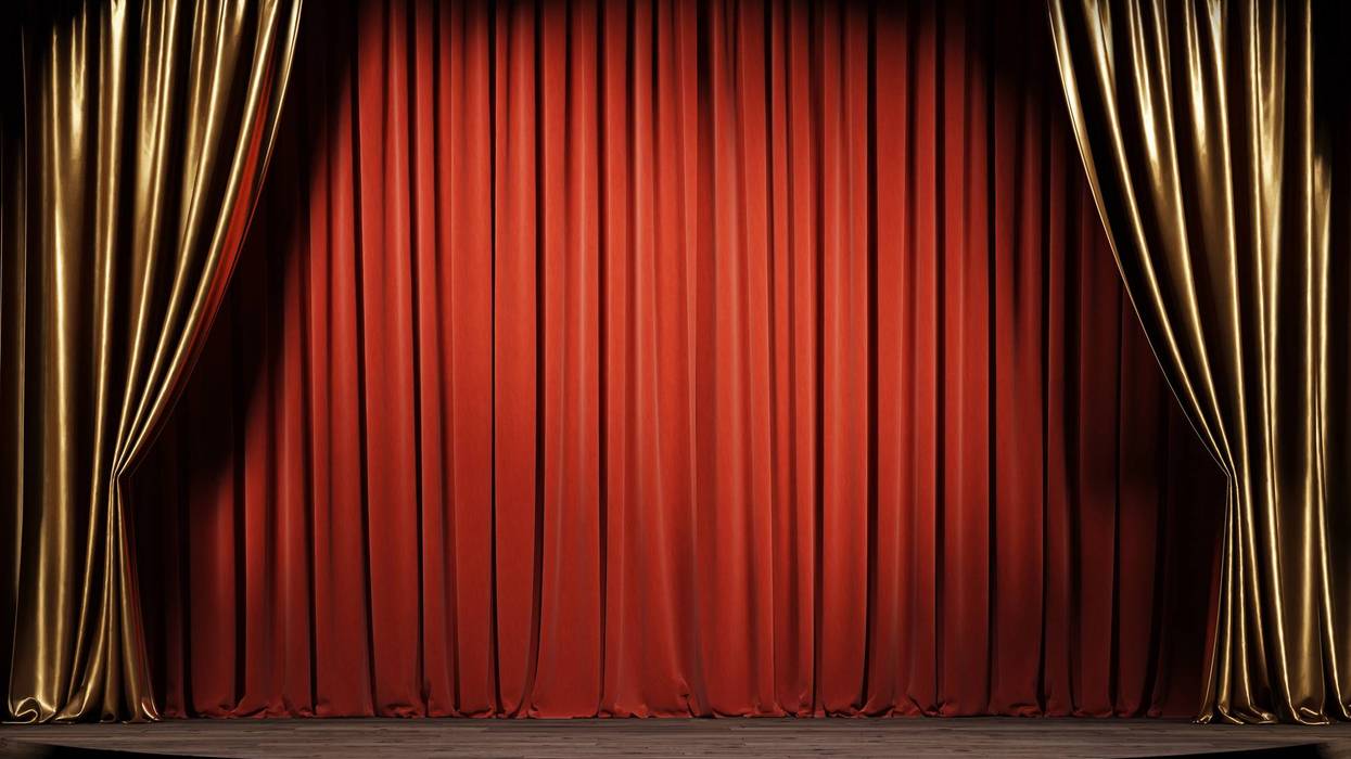 Empty theater stage with red and gold curtains.