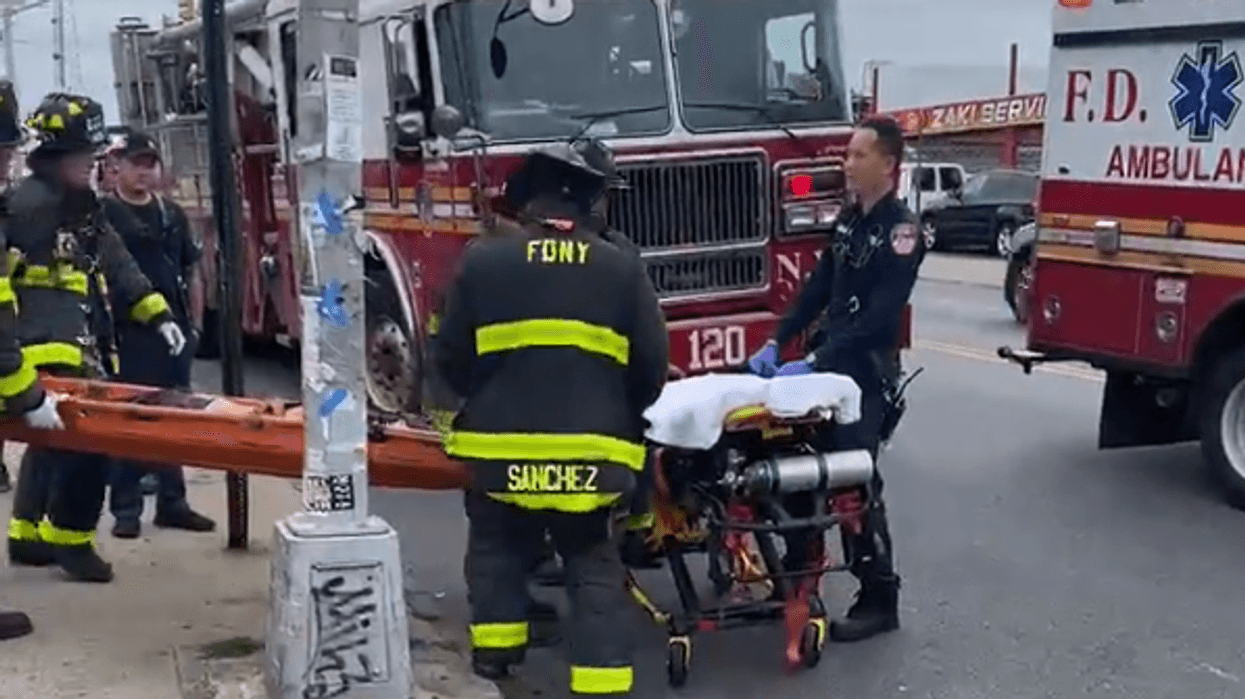 EMS and other FDNY personnel work to transport a gurney with one of the teenagers into an ambulance.