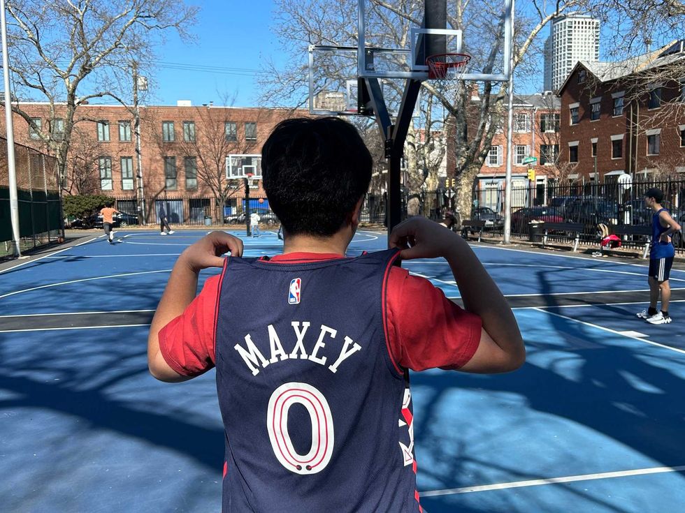 Eric, a ninth-grader from Chinatown, proudly displays the Tyrese Maxey jersey he got for Christmas.