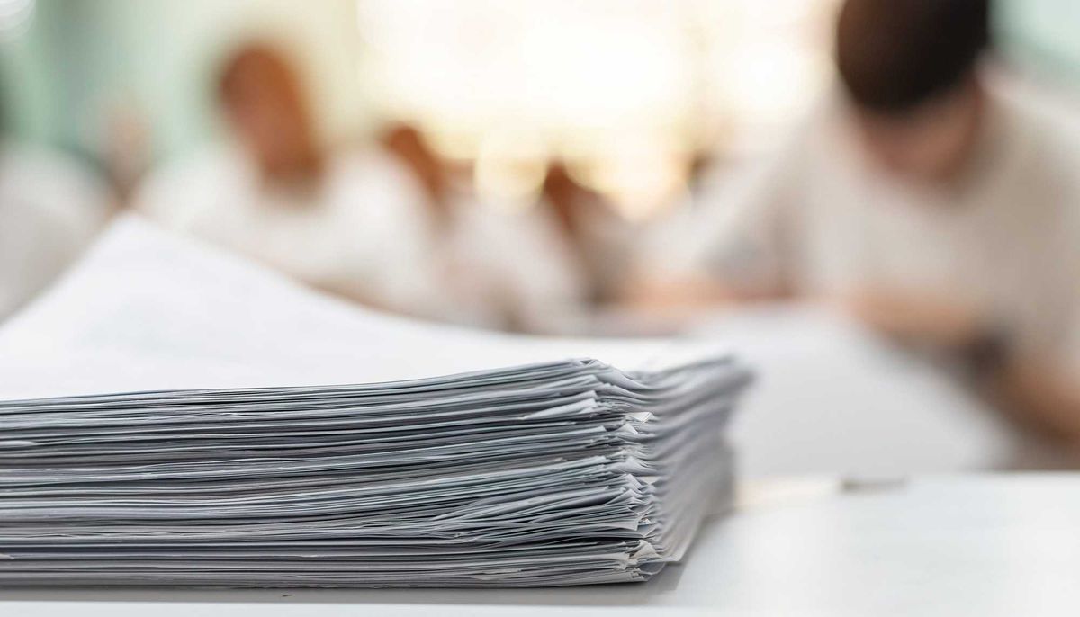 Exam answer sheet or application paper blurry view on table in examination room with blur education background of school university students taking exam test writing answer in seat row with stress