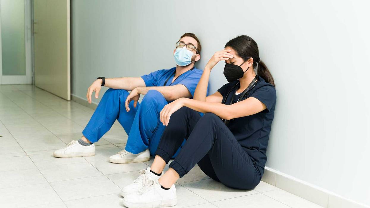 Exhausted nurse and doctor with face masks resting in the hospital aisle. Medical staff feeling tired