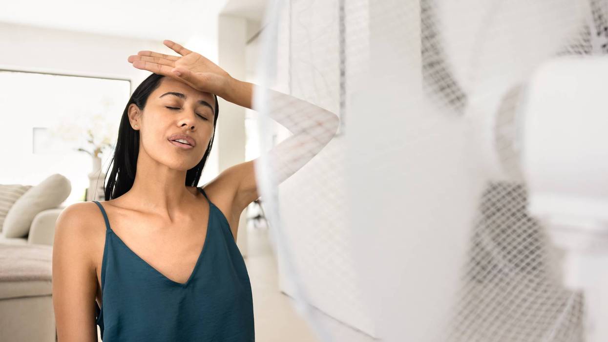 Exhausted overheated young girl cooling down at electric fan