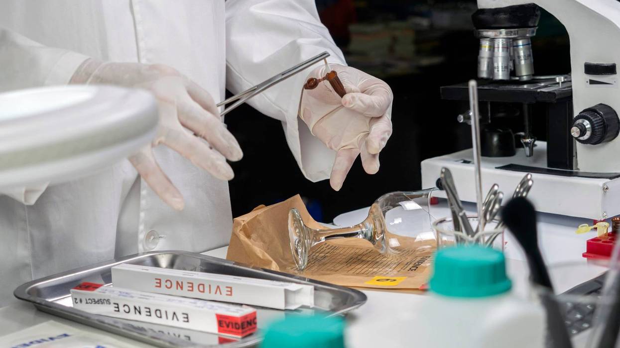Expert gets blood sample from a broken glass cup in a crime lab,