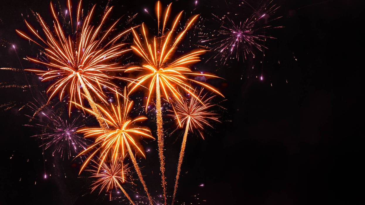 Exploding orange and purple fireworks against a dark night sky.