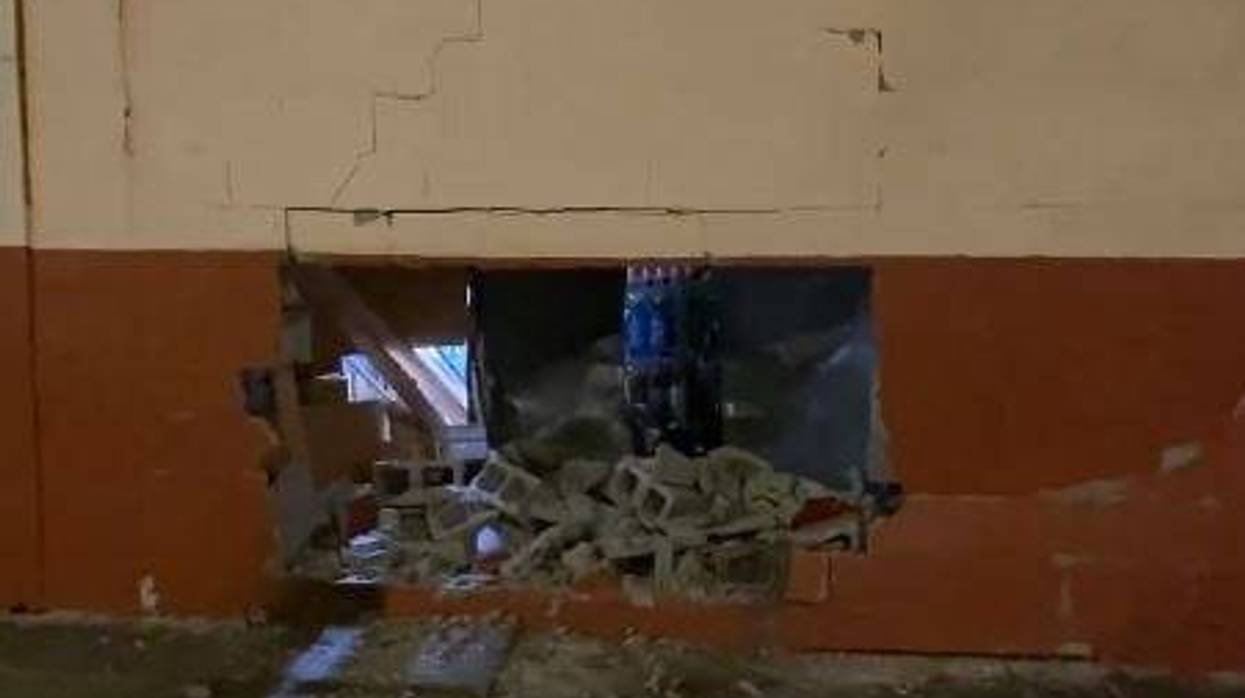 Exterior brick wall of a Detroit liquor store with a sizable hole in it from what is assumed to be an attempted robbery.