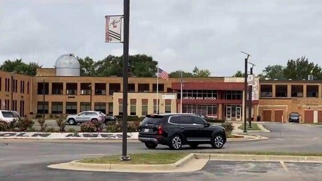 Exterior shot of Lincoln High School in Warren. A two-story brick building with a main section and two L-shaped wings. The school is empty. A few vehicles are parked out in front.