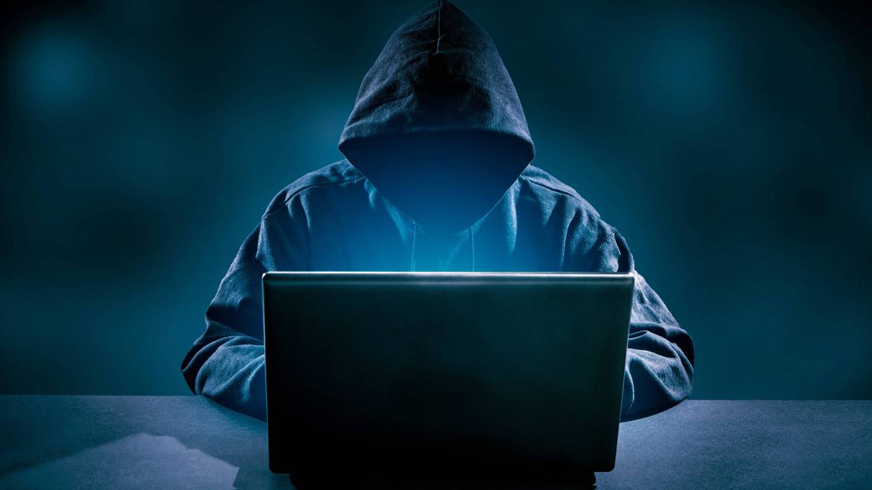 Faceless man in hood on computer