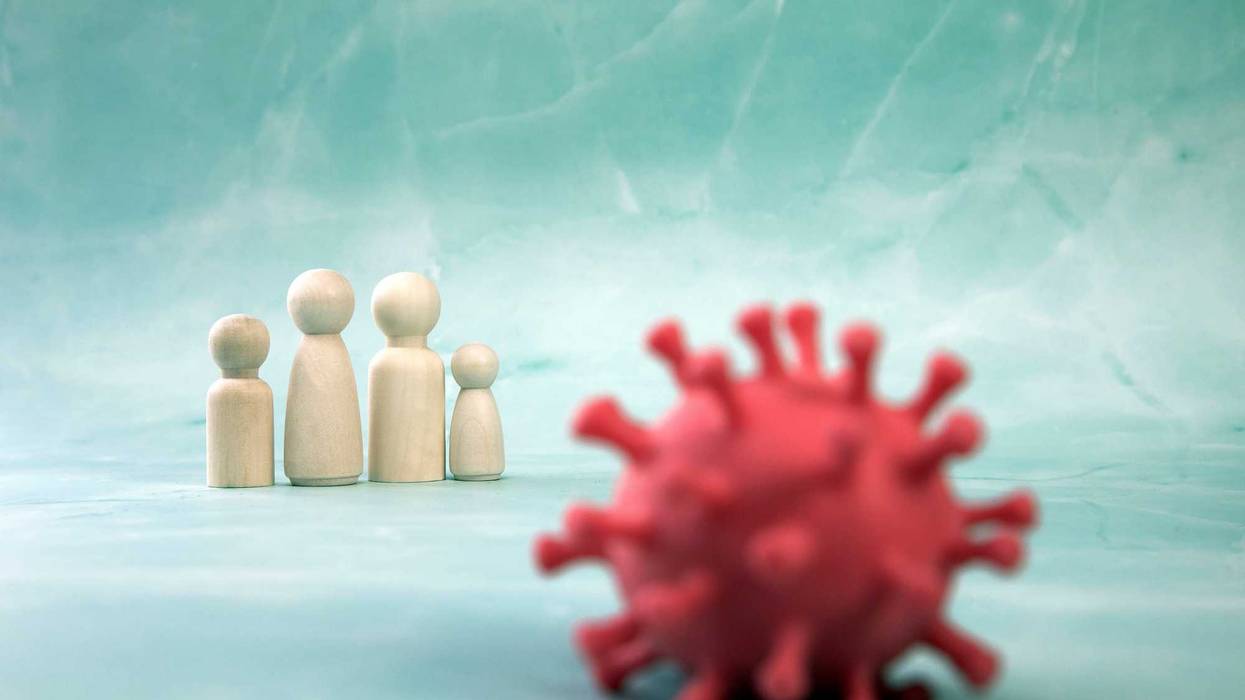 Family of toys in background, red omicron variant of SARS Cov_2 in foreground.