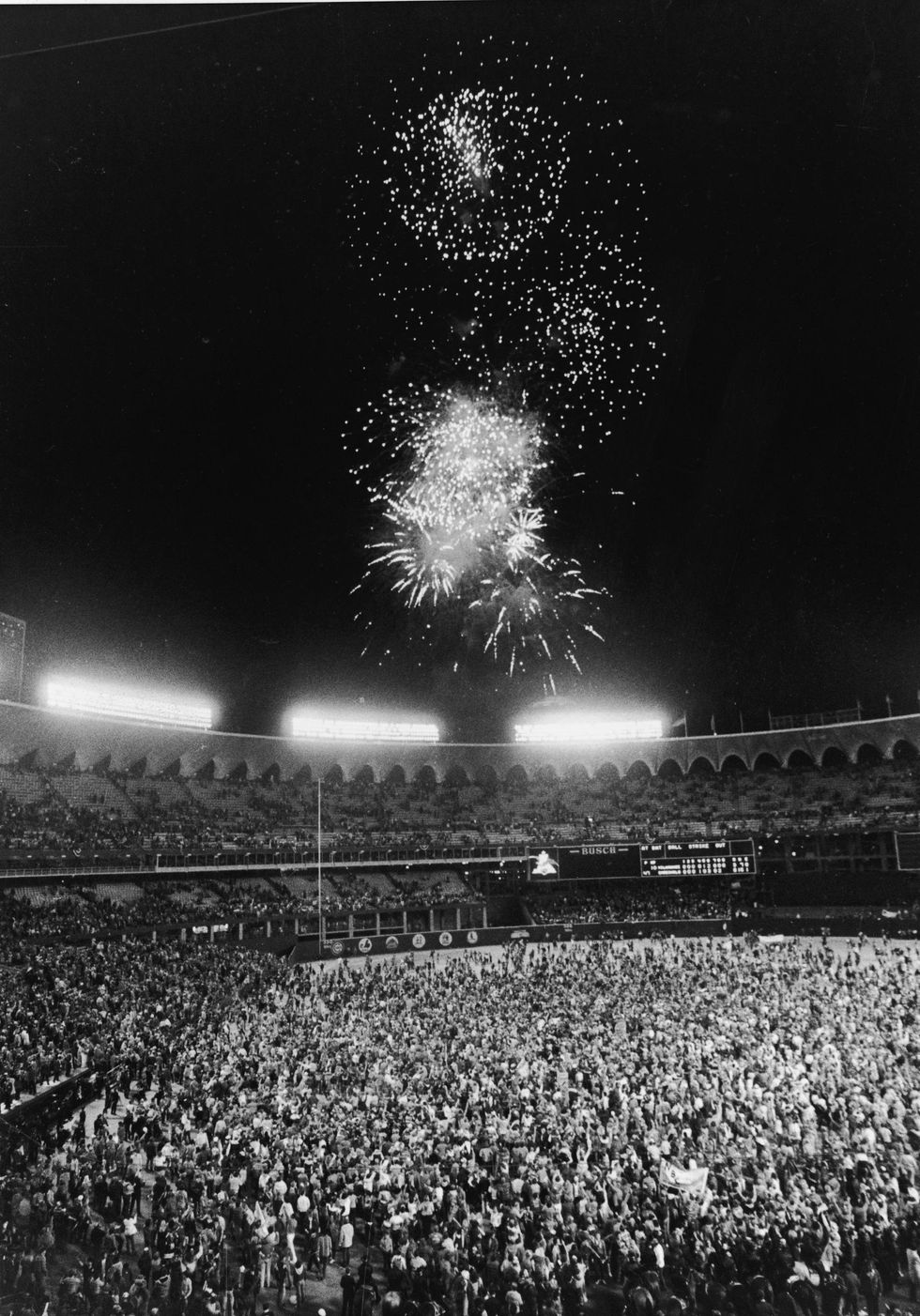 Fans pour onto the field at Busch Stadium at the conclusion of the World Series as fireworks blast overhead, St. Louis, Missouri, October 20, 1982