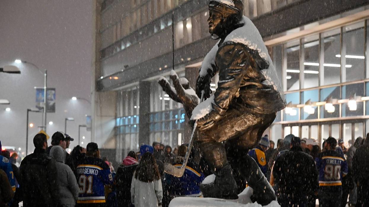 Fans wait in line to enter the Enterprise Center as snow falls prior to a game between the St. Louis Blues and the Colorado Avalanche.