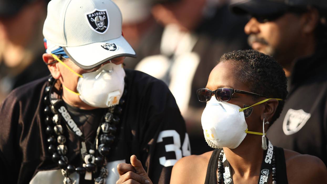 Fans wear face masks in the stands during the NFL game between the Oakland Raiders and the Los Angeles Chargers at Oakland-Alameda County Coliseum on November 11, 2018 in Oakland, California.