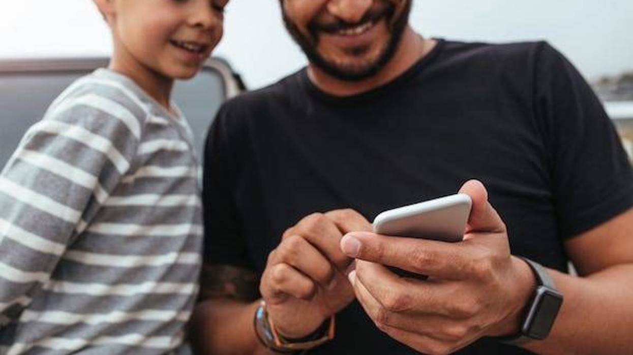 Father and son in front of the car using smart phone