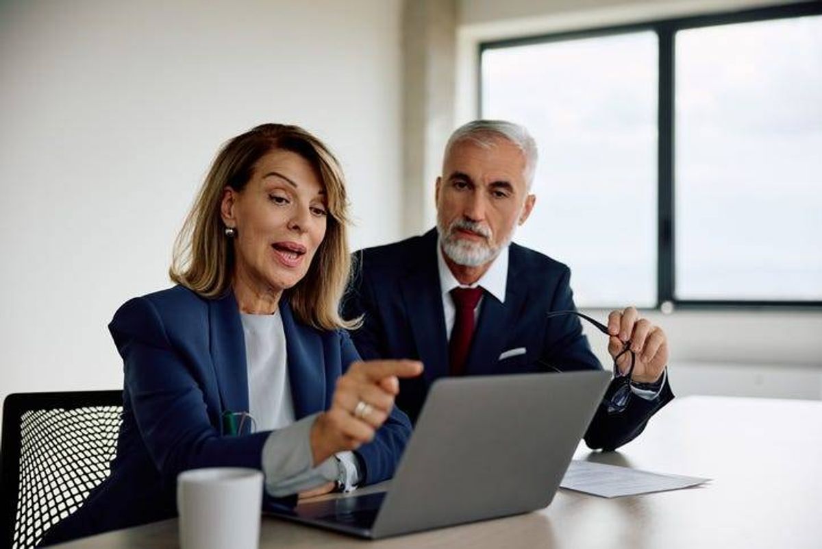Female CEO and her coworker using laptop while working in the office. Copy space.