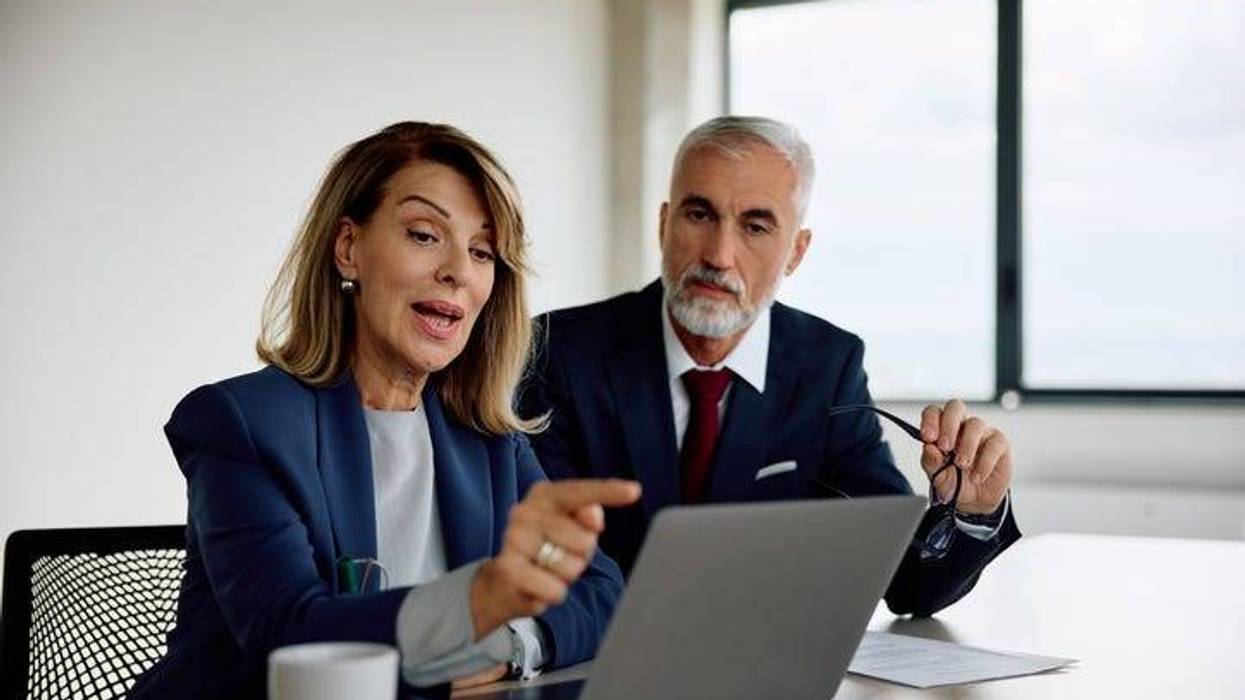 Female CEO and her coworker using laptop while working in the office. Copy space.
