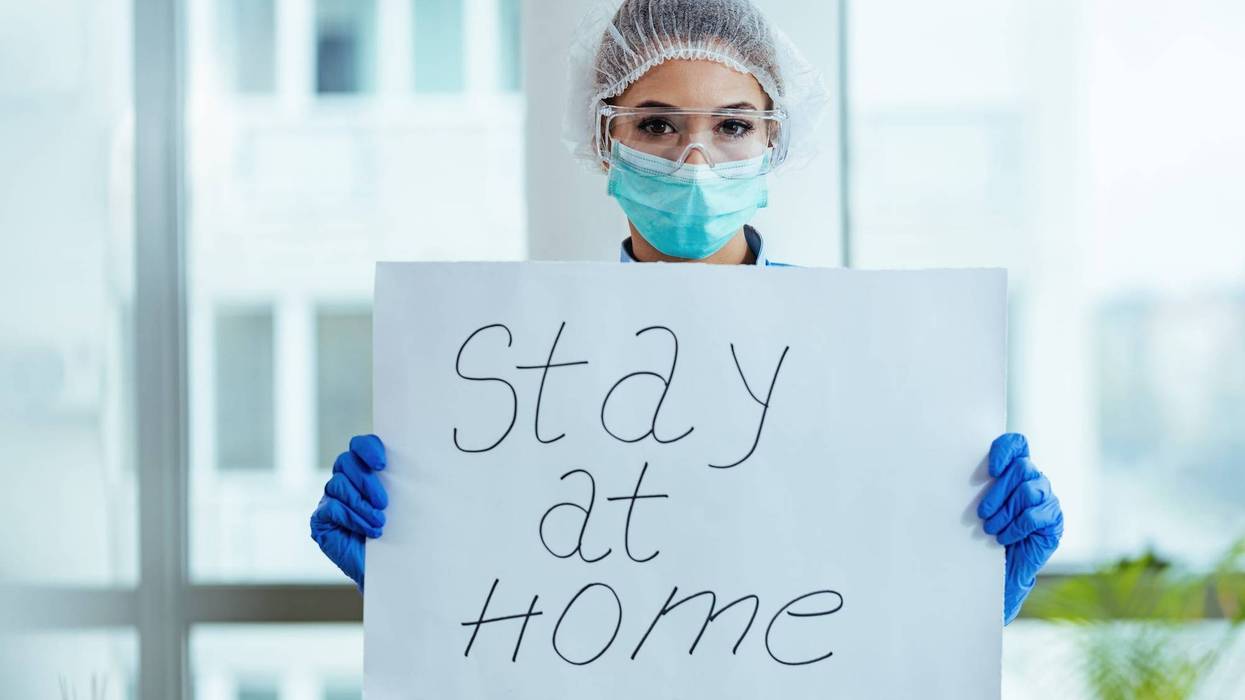 Female doctor holding placard with stay at home message as appeal for social distancing during a coronavirus epidemic.