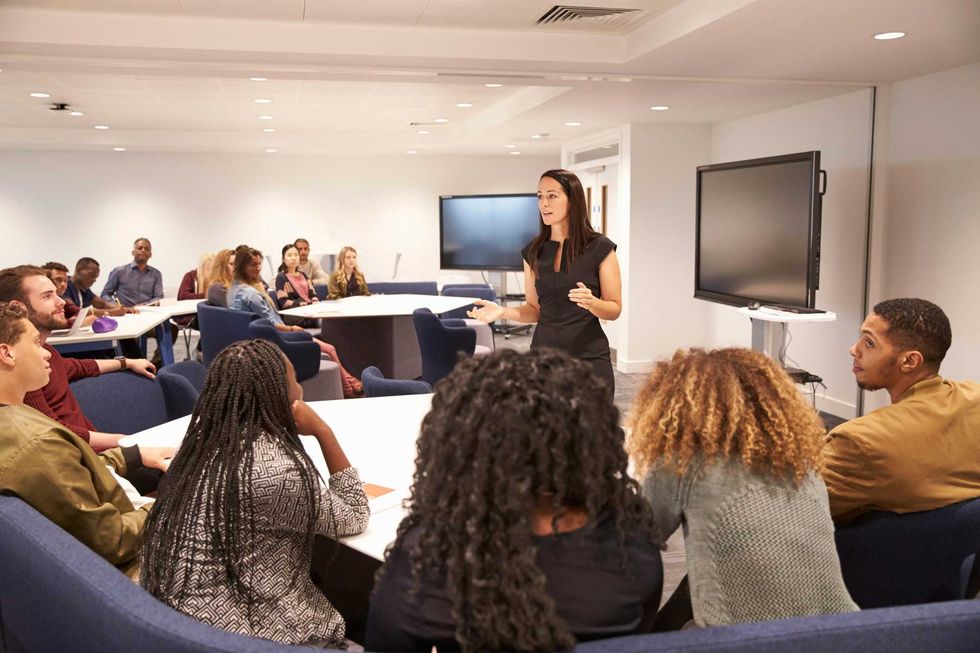 Female teacher addressing university students in a classroom (stock photo)