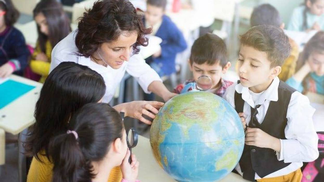 female teacher and students looking the globe