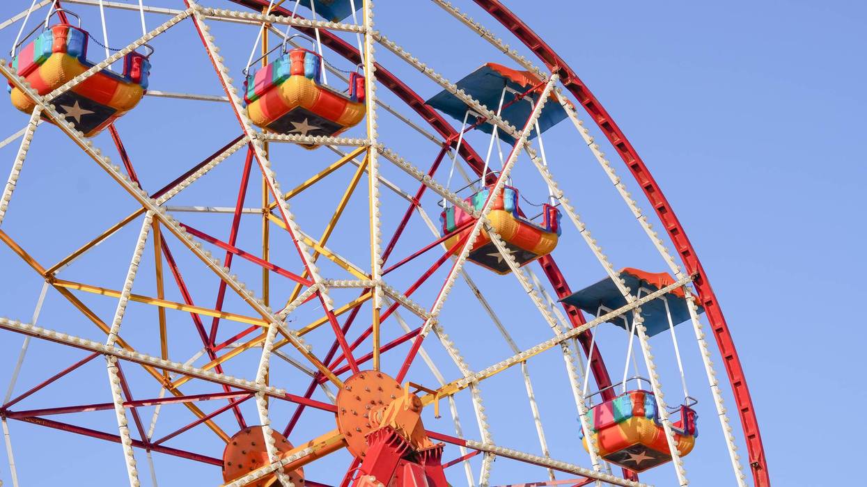 Ferris wheel with colorful cabins rotating against a clear blue sky.