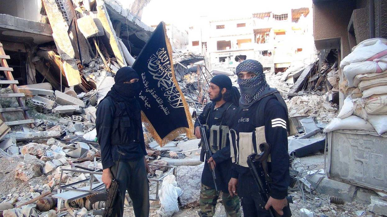 Fighters from the al-Qaida group in the Levant, Al-Nusra Front, stand among destroyed buildings near the front line with Syrian government solders in Yarmuk Palestinian refugee camp, south of Damascus on September 22, 2014.