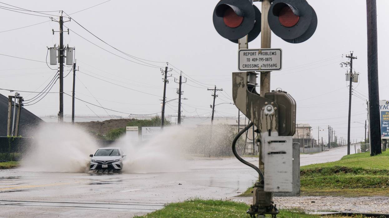 FILE: A car speeds through a flooded street ahead of the Tropical Storm Nicholas on September 13, 2021 in Galveston, Texas.