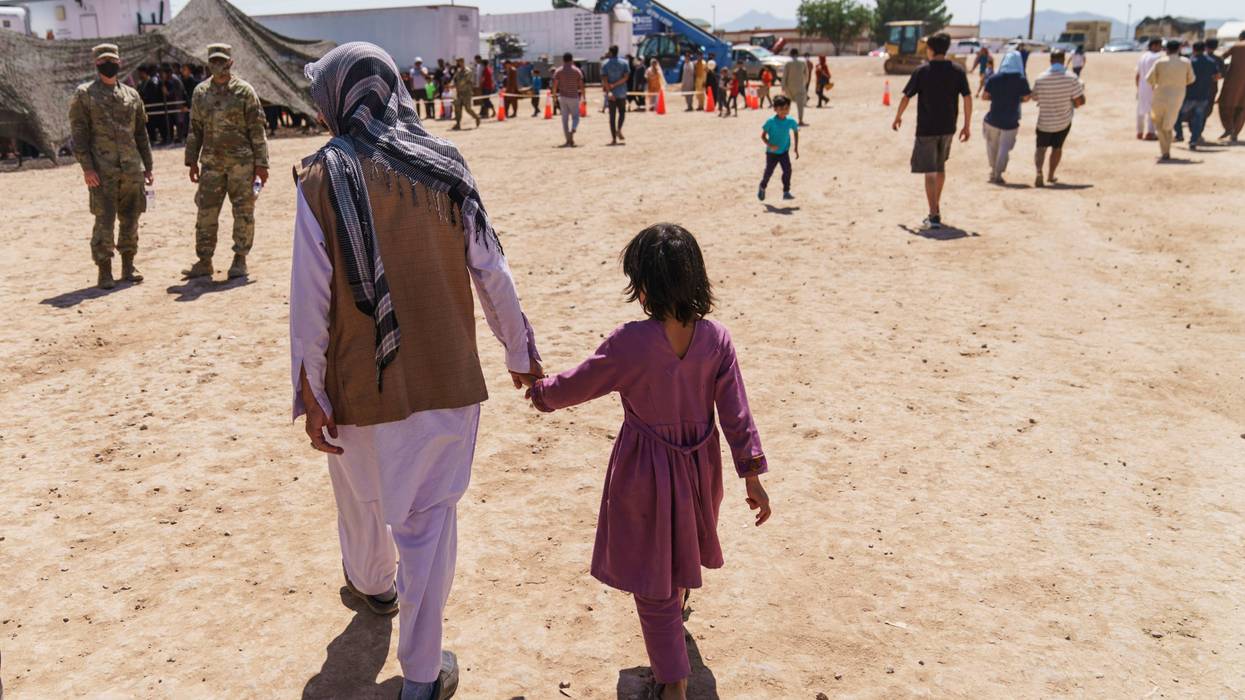 FILE - A man walks with a child through Fort Bliss' Doña Ana Village where Afghan refugees are being housed, in New Mexico, Friday, Sept. 10, 2021.