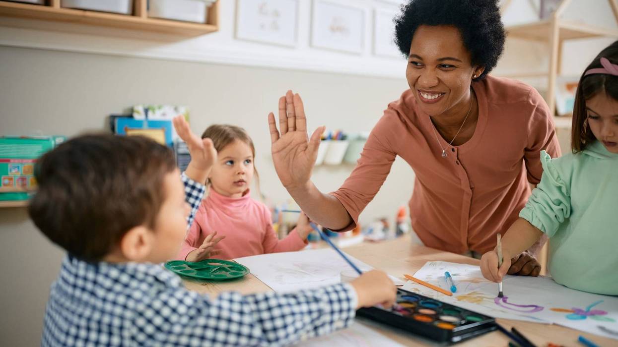 FILE: A small boy giving high-five during art class at kindergarten.
