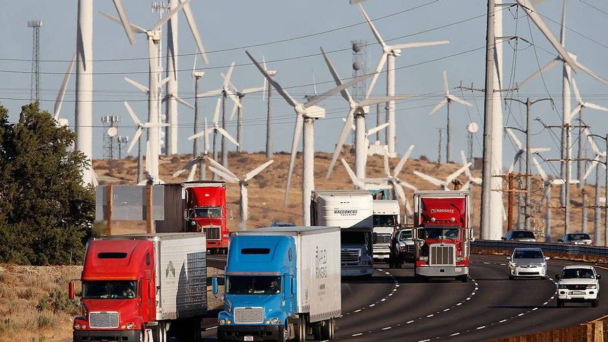 FILE - Emissions-producing diesel trucks and cars pass non-polluting windmills along the 10 freeway on December 8, 2009 near Banning, Calif.