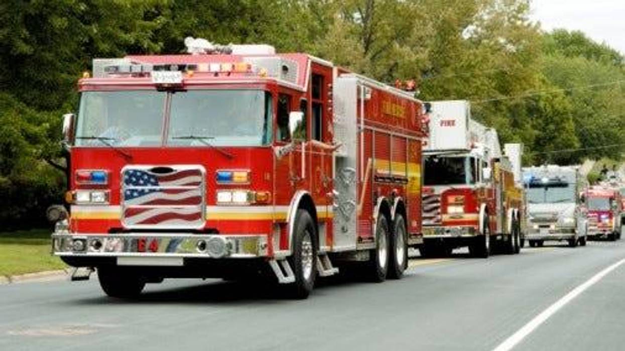 FILE: Fire trucks drive down a street.