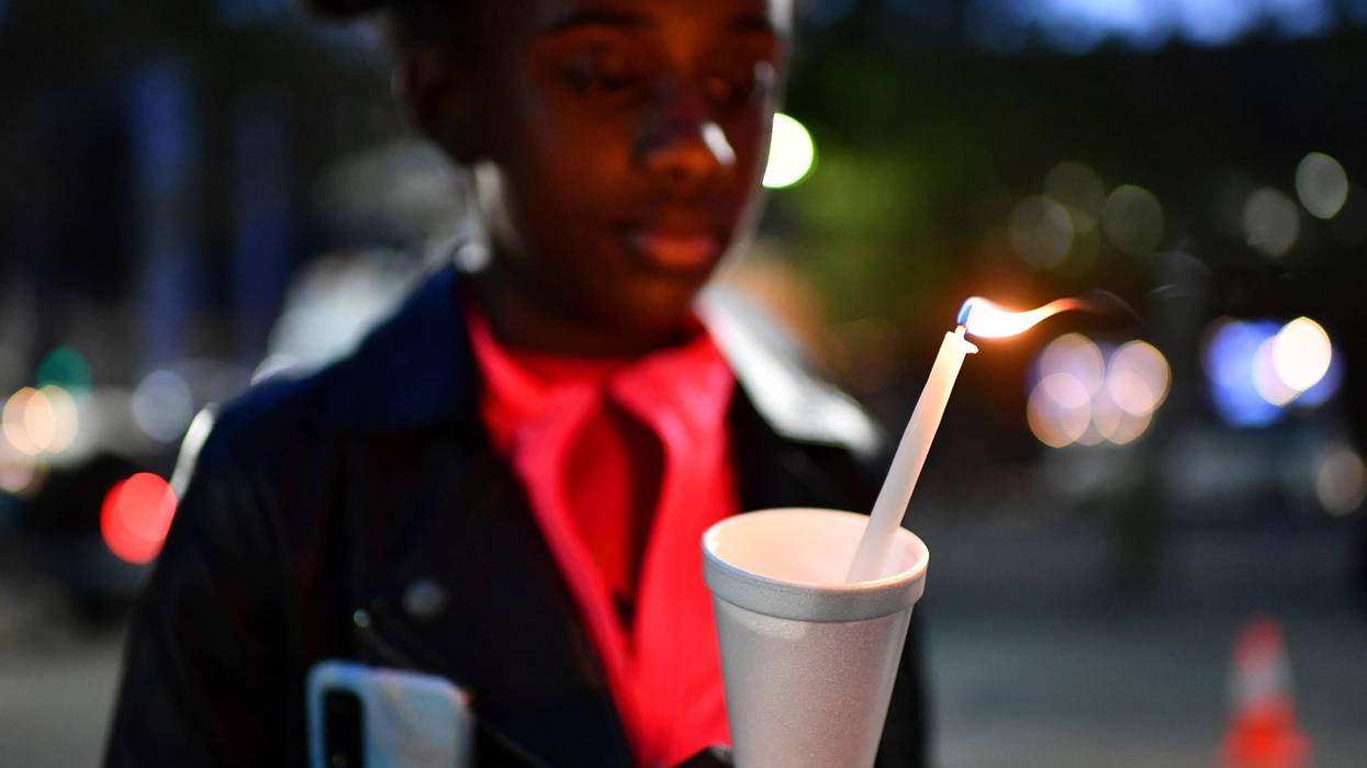 FILE - Gabrielle Knox, 9, of Sacramento, stares at the flame of a candle during a vigil held at Ali Youssefi Square in Sacramento, Calif., late Monday, April 4, 2022. Multiple people were killed and injured after a shooting that occurred early Sunday.