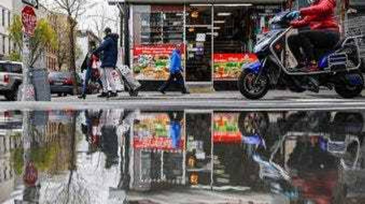 FILE - In this April 27, 2020, file photo, pedestrians and motorists wear personal protective equipment as they pass a small grocery that is one of the few businesses open on the street in New York. (AP Photo/John Minchillo, File)