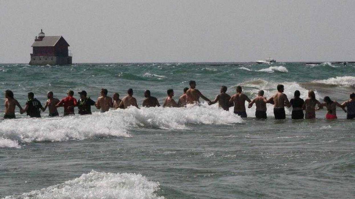 FILE - In this Aug. 5, 2018 file photo, beachgoers help Grand Haven Department of Public Safety officers form human chains to search for missing people in Lake Michigan at Grand Haven State Park in Grand Haven, Mich. More drownings have been reported in the Great Lakes so far in 2021 than by this time last year, prompting officials to urge swimmers to practice water safety measures. As of July 2, there were 32 drownings in the Great Lakes, compared to 25 as of July 4, 2020, according to data collected by the Great Lakes Surf Rescue Project.