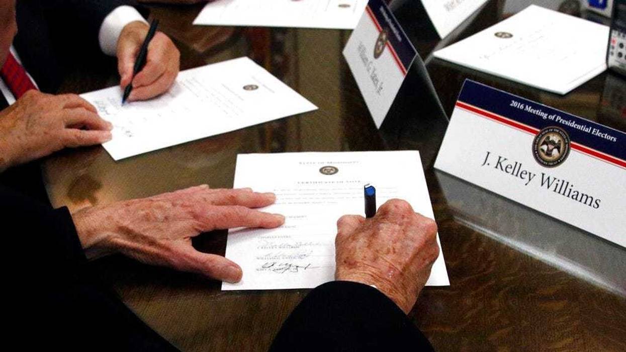 FILE - In this Dec. 19, 2016, file photo members of the Mississippi Electoral College sign certificates of vote in the process of formally casting their electoral votes in the 2016 General Election