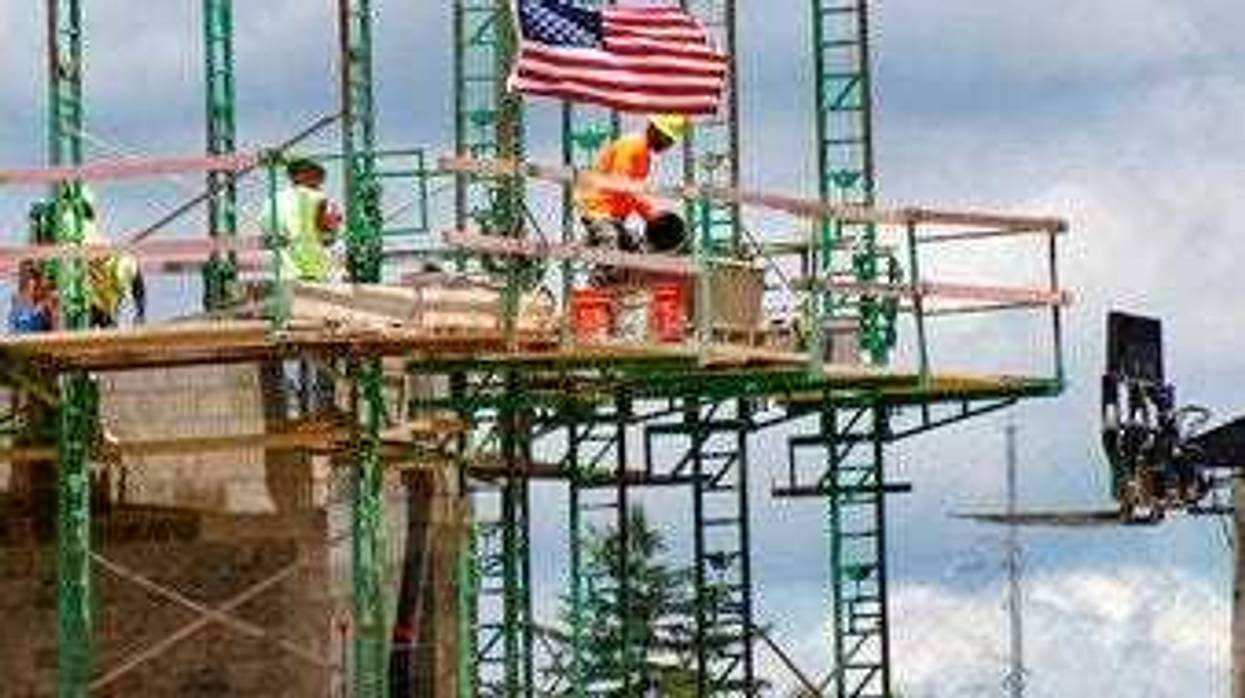 FILE - In this June 11, 2020 file photo, workers on scaffolding lay blocks on one of the larger buildings at a development site where various residential units and commercial sites are under construction. (AP Photo/Keith Srakocic, File)