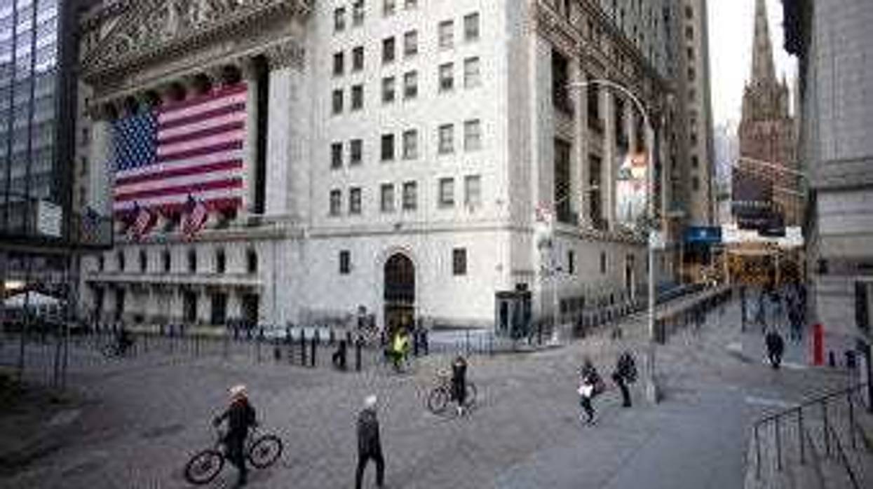 FILE- In this March 18, 2020, file photo a few people walk on Wall Street in front of the New York Stock Exchange in New York. (AP Photo/Mark Lennihan, File)