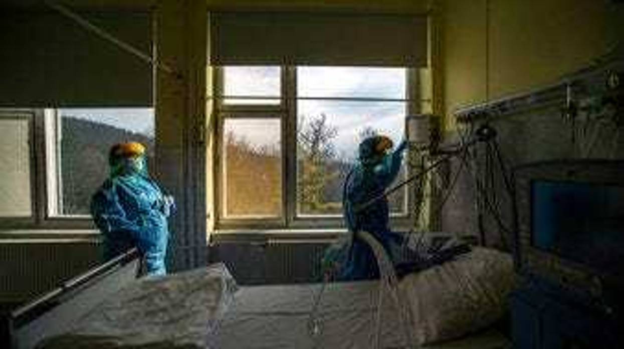 FILE - In this March 24 file photo, medical staff members check a ventilator in protective suits at the care unit for the new COVID-19 infected patients inside the Koranyi National Institute of Pulmonology in Budapest. (Zoltan Balogh/MTI via AP, File)