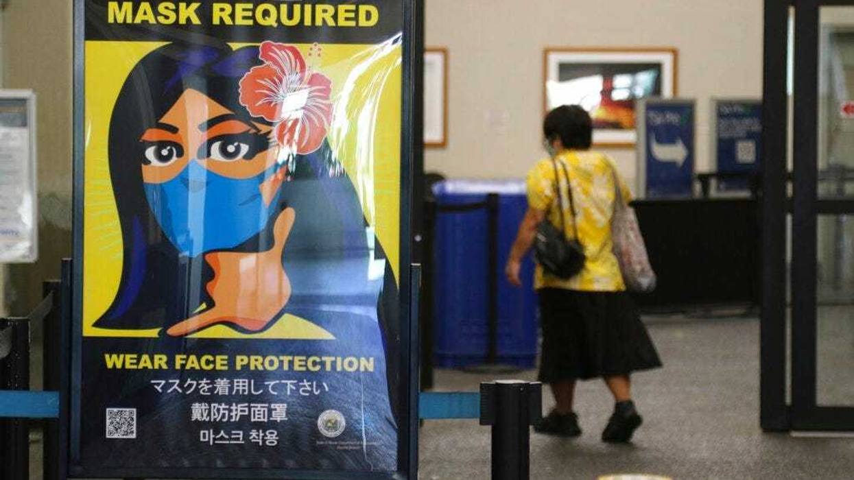 FILE - In this Oct. 2, 2020 file photo, a woman walks into the international airport in Honolulu amid a quarantine rule that effectively shut down the tourism industry in the state.