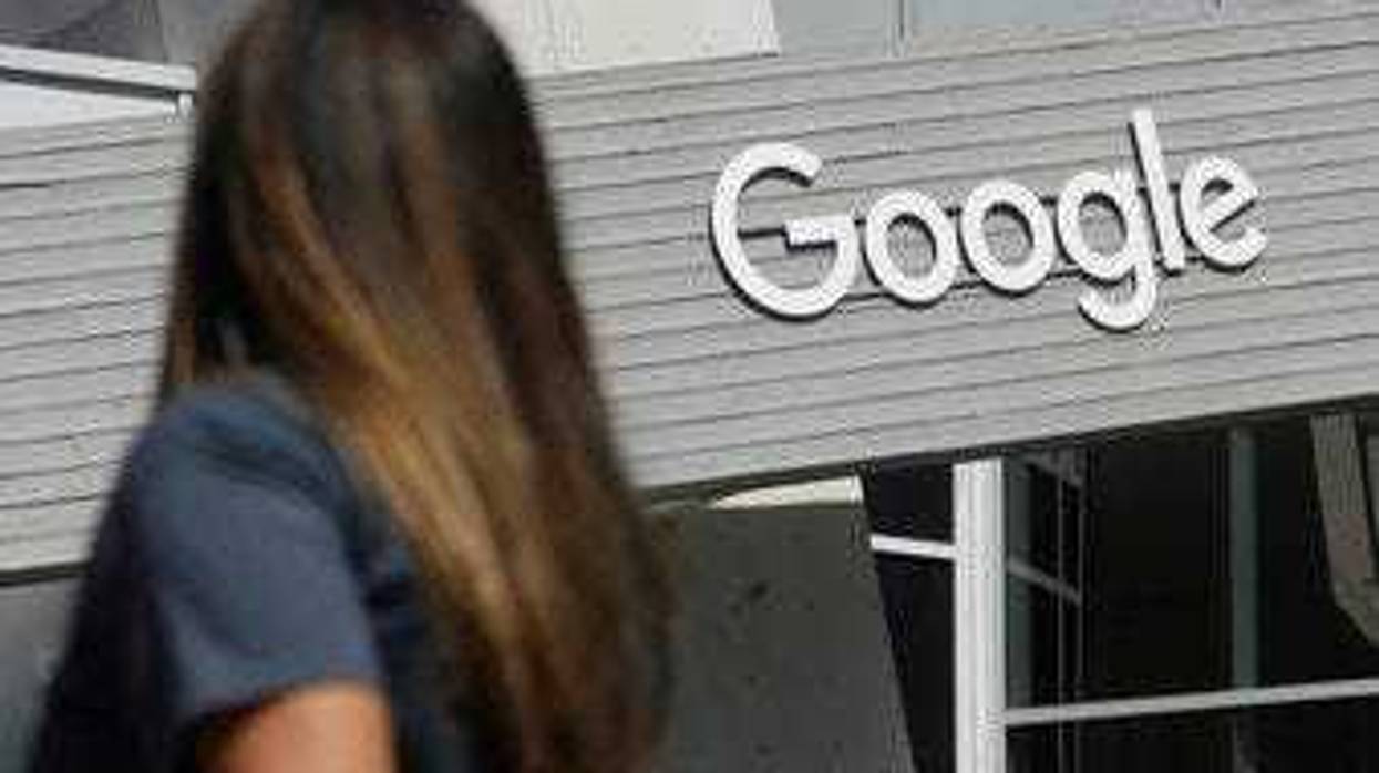 FILE - In this Sept. 24, 2019, file photo, a woman walks below a Google sign on the campus in Mountain View, Calif. New Mexico is suing Google over allegations that the tech company is illegally collecting personal data. (AP Photo/Jeff Chiu, File)