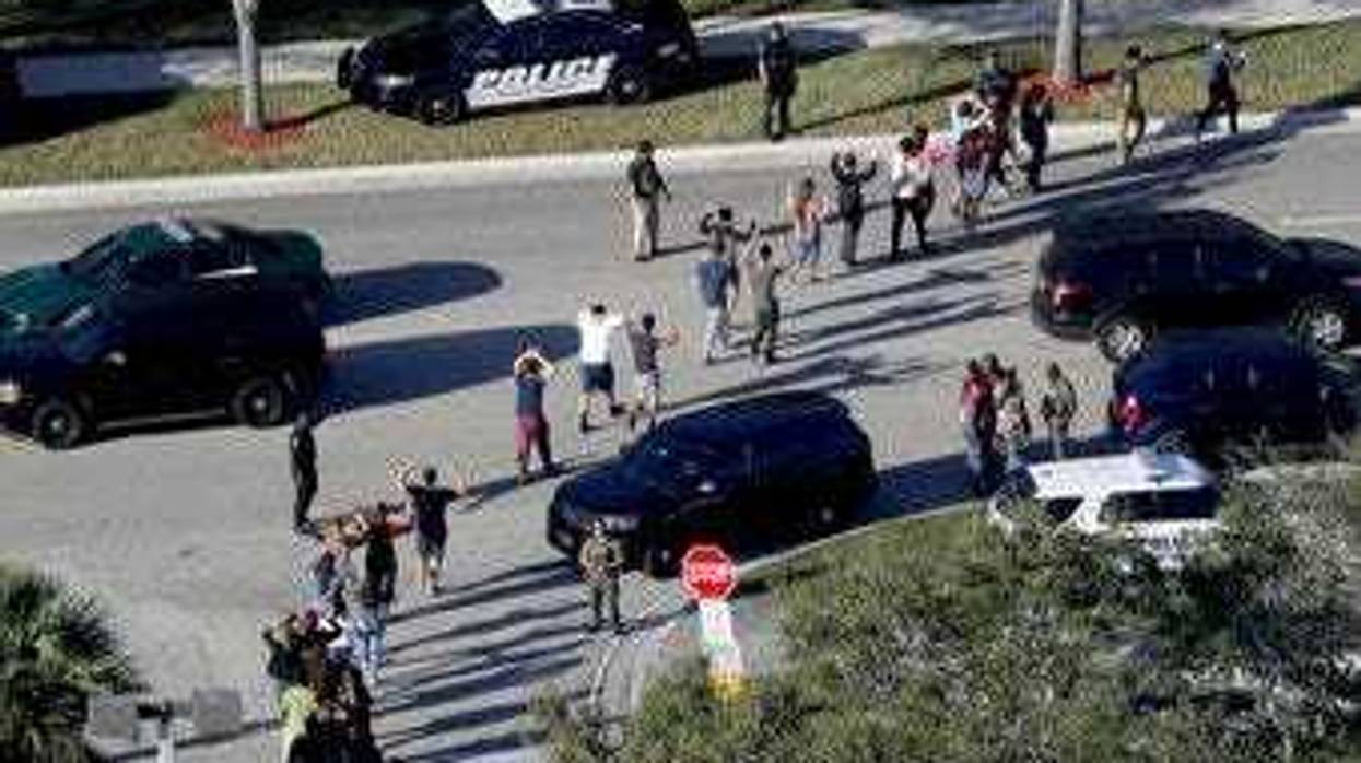 FILE - In this Wednesday, Feb. 14, 2018, file photo, students hold their hands in the air as they are evacuated by police from Marjory Stoneman Douglas High School in Parkland, Fla. (Mike Stocker/South Florida Sun-Sentinel via AP, File)