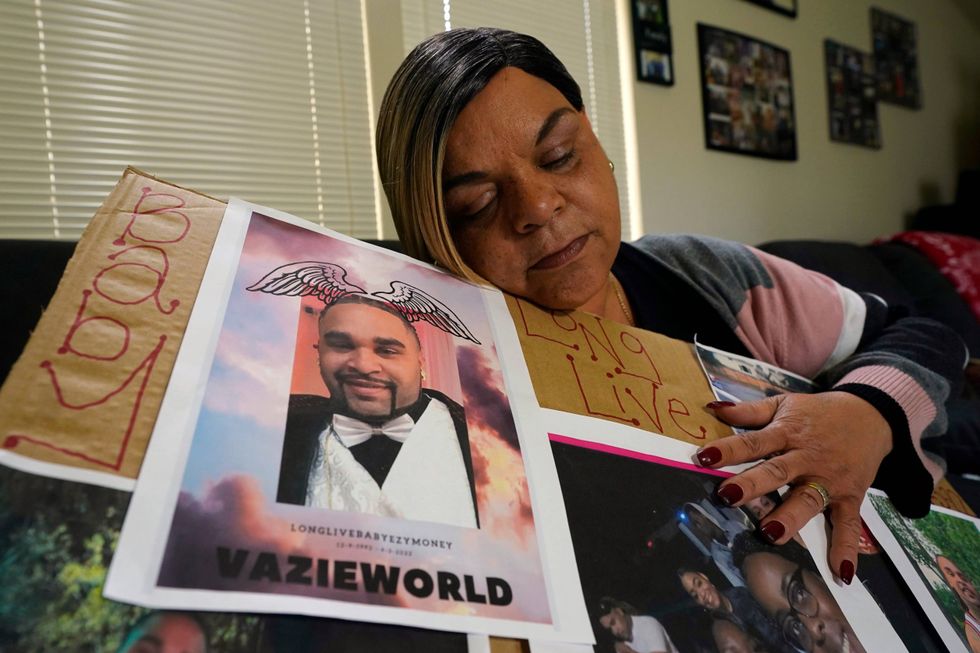 FILE - Penelope Scott holds a collection of family photos including one of her son, De