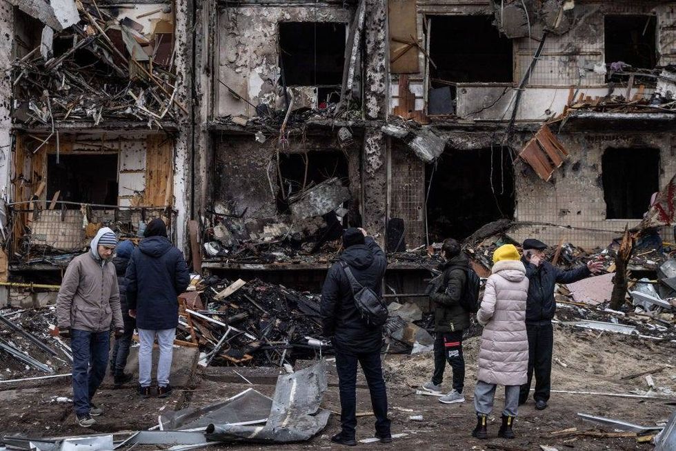 FILE - People look at the exterior of a damaged residential block hit by an early morning missile strike on Feb. 25, 2022 in Kyiv, Ukraine. The day before, Russia began a large-scale attack on Ukraine, with Russian troops invading the country from the north, east and south, accompanied by air strikes and shelling. The Ukrainian president said that at least 137 Ukrainian soldiers were killed by the end of the first day.