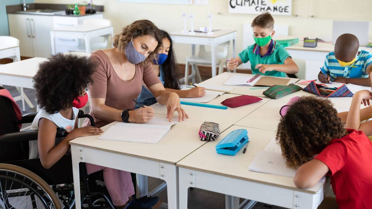 File photo of a female teacher wearing face mask at school, teaching children at school classroom during mask mandates brought on by the coronavirus pandemic.