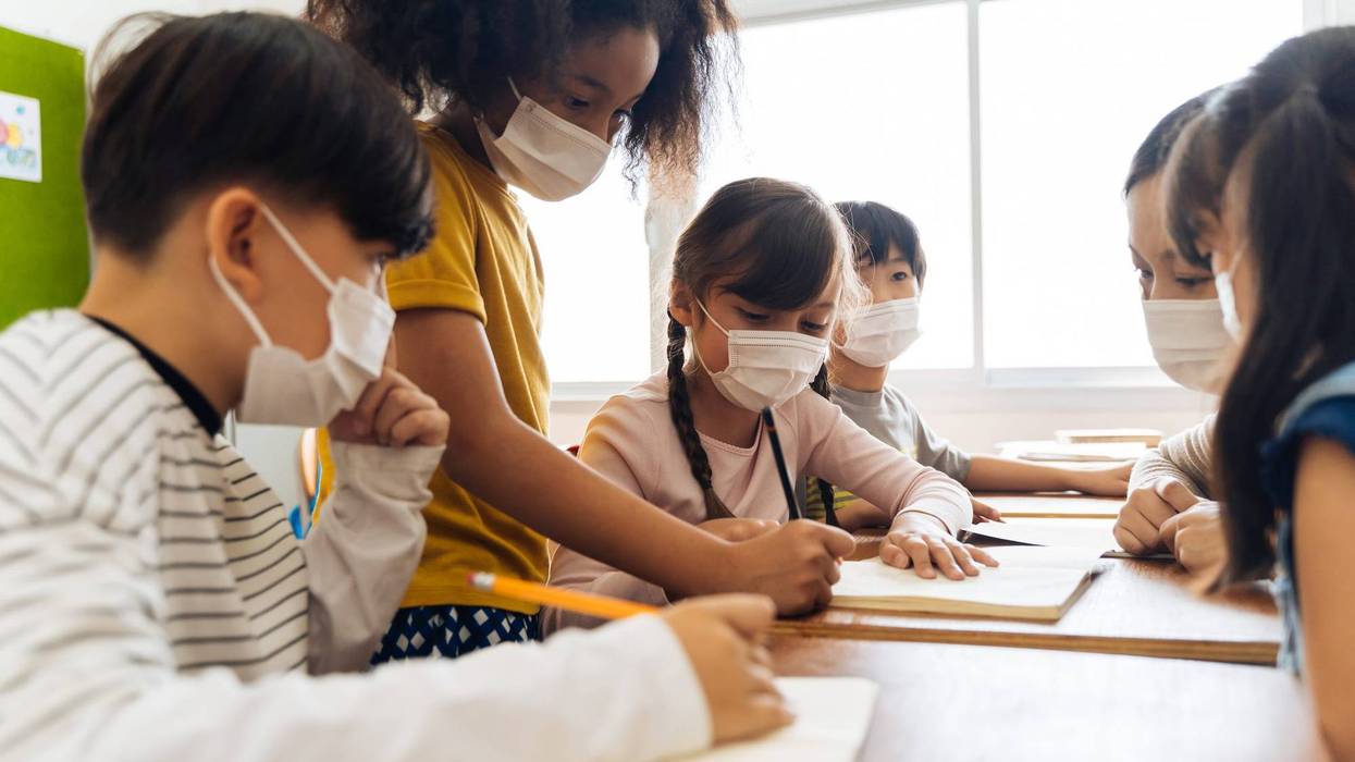 File photo of students wearing masks while in a group at school.