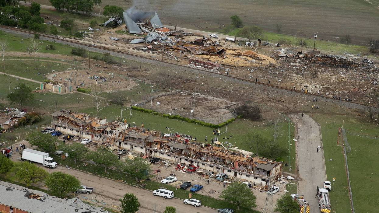 File Photo: Search and rescue workers comb through what remains of a 50-unit apartment building (foreground) the day after an explosion at the West Fertilizer Company (background) destroyed the building April 18, 2013 in West, Texas. According to West May