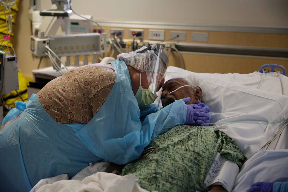 FILE - Romelia Navarro, 64, weeps while hugging her husband, Antonio, in his final moments in a COVID-19 unit at St. Jude Medical Center in Fullerton, Calif., July 31, 2020.