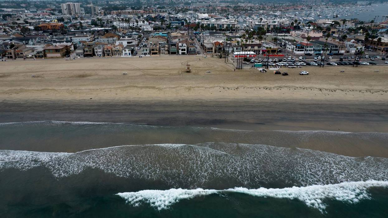 FILE - This aerial image taken with a drone, shows the closed beach after oil washed up in Newport Beach, Calif., on Oct. 7, 2021. A pipeline operator says it has reached a settlement with tour operators, fishermen and other businesses that sued after a crude oil spill off the Southern California coast last year. Amplify Energy says in a statement Thursday, Aug. 25, 2022, that claims have been settled in a class-action lawsuit filed by businesses affected by the October spill of about 25,000 gallons (94,600 liters) of crude into the Pacific Ocean.