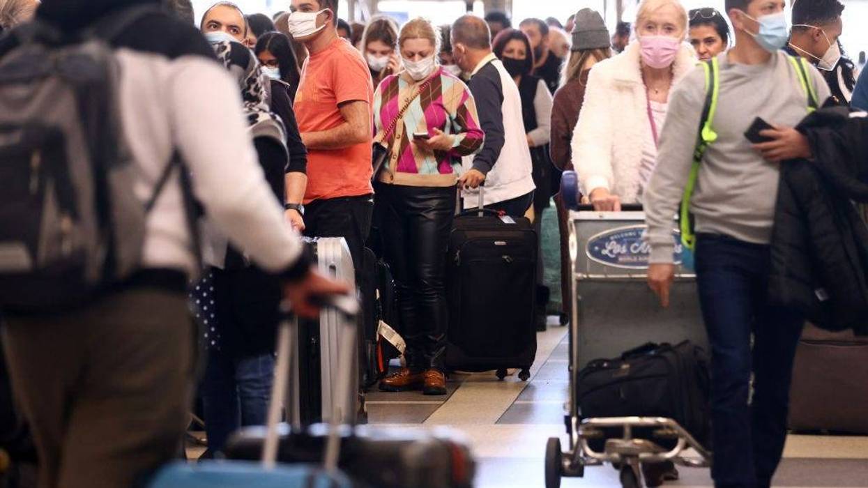 FILE - Travelers gather in the international terminal at Los Angeles International Airport (LAX) amid a surge in omicron variant cases on December 21, 2021 in Los Angeles.