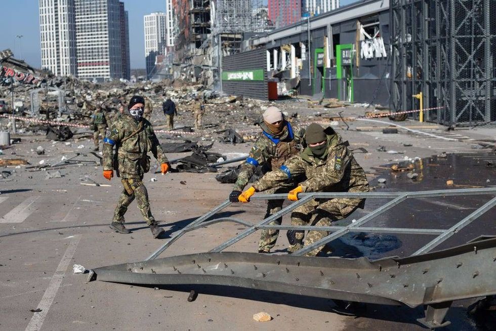 FILE - Ukrainian servicemen are seen at the explosion site as a result of a rocket strike into the shopping mall on March 21, 2022 in Kyiv, Ukraine. As Russia