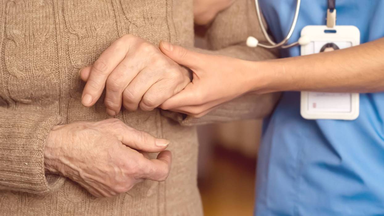 FILE: Young woman holds elderly patient's hands.